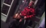Junge Blondine kniet in Netzstrumpfhose vor älterem Mann in rotem Hemd und bläst ihn tief auf der Haustreppe.
