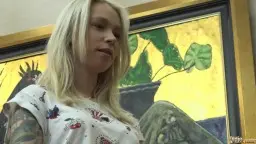 Blonde mit Tattoo-Shirt steht neben grauhaarigem Mann im Wohnzimmer