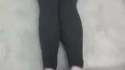 Nahaufnahme der Beine in engen schwarzen Leggings auf hellem Teppichboden
