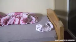 Nacktes dunkelhaariges Mädchen mit nassen Haaren und verklärtem Gesichtsausdruck steht seitlich vor heller Wand
