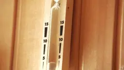 Brünette mit langen Haaren im Saunaraum, Thermometer an Holzwand