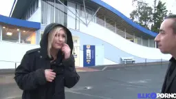 Gina Wild im schwarzen Hoodie auf einem verlassenen Parkplatz im Gespräch mit einem Mann