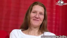 Reife blonde Mutter mit langen Haaren lächelt verführerisch auf roter Couch
