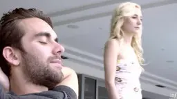 Bruder liegt entspannt auf dem Sofa, während seine blonde Schwester verführerisch daneben steht.